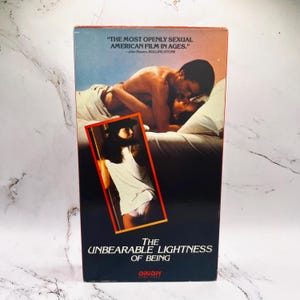May include: A vintage VHS tape for the film "The Unbearable Lightness of Being." The cover features a romantic scene and a smaller image of a person. Text includes a quote from Rolling Stone and the Orion logo.
