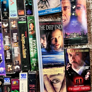 Może przedstawiać: Kolekcja r&oacute;żnych kaset wideo VHS z tytułami takimi jak The Brotherhood III, Vertigo, The Order, Patrick, The Deep End, Wolf, The Puppet Masters i Endless Night, pokazana z widocznymi grzbietami i przednimi okładkami.