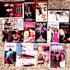 May include: A selection of VHS tapes and DVDs, including films such as "Touched by an Angel," "Shout," "Heartbreakers," and "Sommersby." The covers showcase actors and actresses, with vibrant graphics and text.