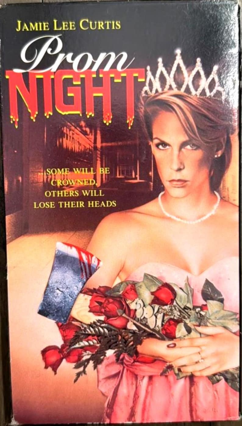 Może przedstawiać: Okładka kasety VHS filmu Prom Night przedstawiająca Jamie Lee Curtis w tiarze i r&oacute;żowej sukience, trzymającą bukiet czerwonych r&oacute;ż oraz zakrwawiony top&oacute;r. Tekst głosi: Jamie Lee Curtis, Prom Night, Some will be crowned, others will lose their heads.