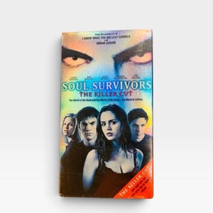 Może przedstawiać: Kaseta VHS z filmem Soul Survivors: The Killer Cut. Okładka przedstawia parę intensywnych oczu u g&oacute;ry, tytuł niebieską czcionką oraz czworo aktor&oacute;w na pierwszym planie. Czerwony ukośny pasek na dole zawiera napis The Killer Cut.