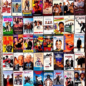 Puede incluir: Una colección de sesenta y tres cintas de video VHS dispuestas en una cuadrícula, que presentan varios títulos de películas como 10 Things I Hate About You, Daddy Day Care, Crocodile Dundee, Nurse Betty, The Full Monty y The Ref, con portadas ilustradas.