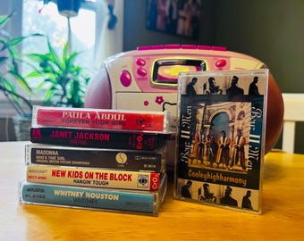May include: A stack of music cassette tapes featuring artists like Paula Abdul, Janet Jackson, Madonna, New Kids on the Block, and Whitney Houston. A pink and white boombox sits in the background, with a Boyz II Men cassette tape in front.