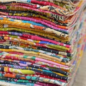 Puede incluir: Una pila de piezas de tela coloridas y estampadas. Los textiles presentan una variedad de colores, incluyendo rojo, rosa, amarillo, verde y azul. Las telas parecen estar cosidas, creando un efecto de capas. La imagen es un primer plano, que muestra la textura y el detalle de los materiales.
