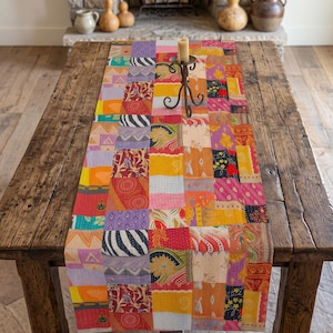 Könnte beinhalten: Ein rechteckiger Tischläufer mit einem Patchwork-Design aus verschiedenen Stoffquadraten in leuchtenden Farben wie Gelb, Rot, Pink, Lila und Orange. Das Textil zeigt vielfältige Muster wie florale, geometrische und gestreifte Motive.