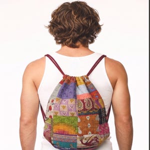 May include: A drawstring backpack featuring a patchwork design with various colorful fabric squares. The bag displays diverse patterns including paisley, floral, and geometric prints in shades of purple, green, orange, and red, with thin maroon straps.