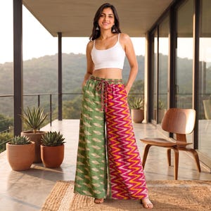Puede incluir: Un top corto blanco sin mangas combinado con pantalones anchos de diseño dividido. La pierna izquierda tiene un patrón de hojas verdes, mientras que la derecha muestra un estampado en zigzag rosa y amarillo vibrante con cintura ajustable.