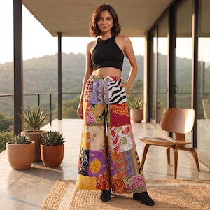 May include: A black sleeveless crop top paired with wide-leg trousers featuring a vibrant patchwork design. The trousers are composed of various colourful fabric panels with diverse floral, paisley, and animal print patterns in shades of red, yellow, and purple.