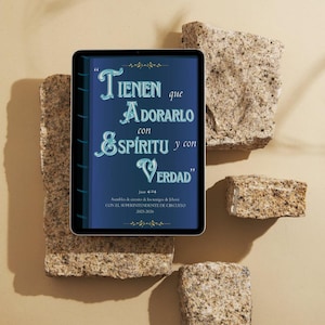 May include: A digital tablet displaying text in Spanish: "TIENEN que ADORARLO con ESPÍRITU y con VERDAD." The tablet is on a beige surface with stone blocks. The text also includes "Juan 4:24" and "Asamblea de circuito de los testigos de Jehová 2025-2026."