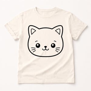 Puede incluir: Camiseta de color crema con un gran contorno negro de una cara de gato de dibujos animados. El gato tiene ojos grandes, bigotes y una boca sonriente. La camiseta tiene mangas cortas y cuello redondo.