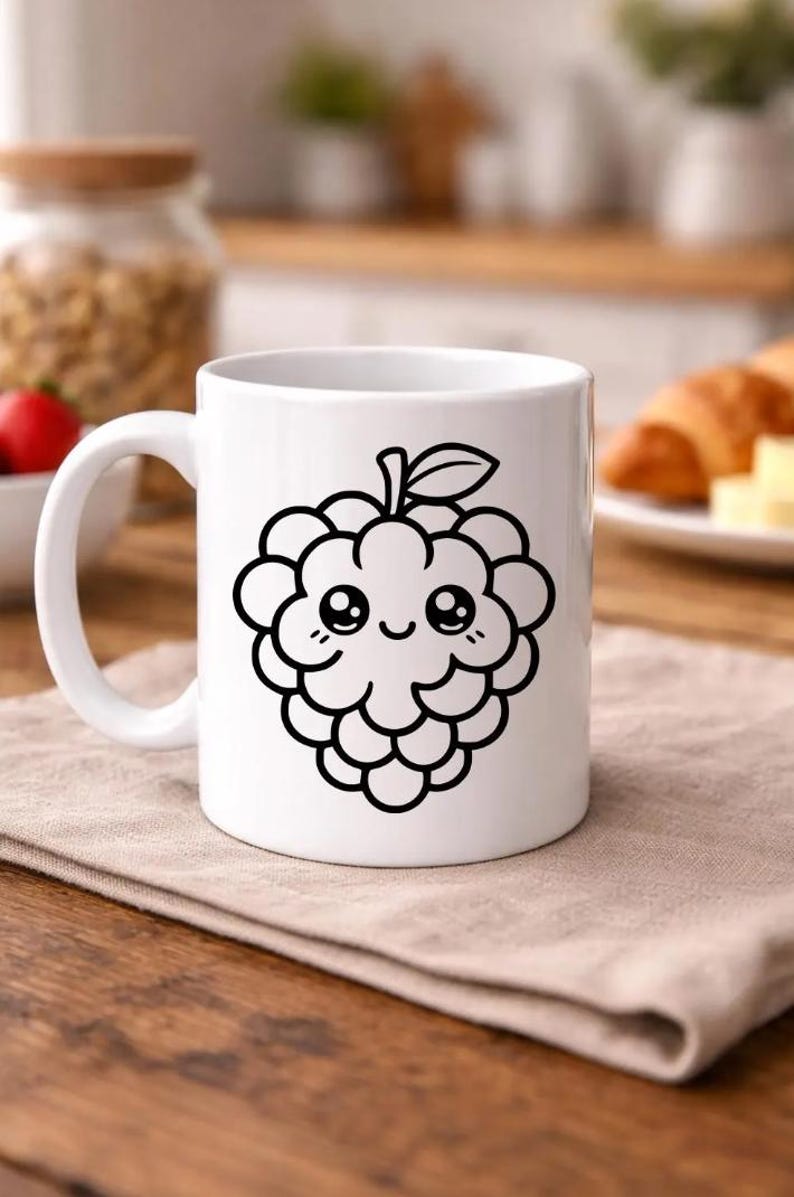 Puede incluir: Taza de cer&aacute;mica blanca con una ilustraci&oacute;n en contorno negro de una frambuesa sonriente, con tallo y hoja. La taza tiene un asa curva y est&aacute; colocada sobre una superficie de madera. Un tarro de frutos secos y un cruas&aacute;n est&aacute;n en el fondo.