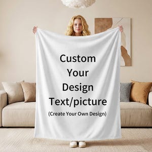Könnte beinhalten: Eine weiße Decke mit dem Text "Custom Your Design Text/picture (Create Your Own Design)" in Schwarz. Die Decke wird von einer Person vor einem beigen Sofa und Kissen gehalten.