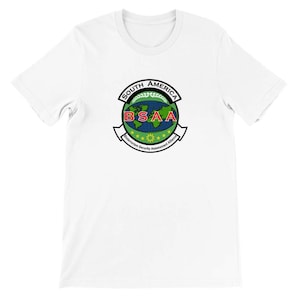 Può includere: T-shirt bianca con un emblema colorato. L'emblema presenta le scritte "SOUTH AMERICA" e "BSAA", un globo, foglie di alloro e il testo "Bioterrorism Security Assessment Alliance".
