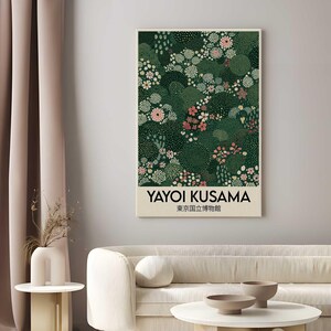 May include: A framed art print featuring a floral design in shades of green, pink, and white. The print includes the text "YAYOI KUSAMA" and Japanese characters. The artwork is displayed in a living room setting.