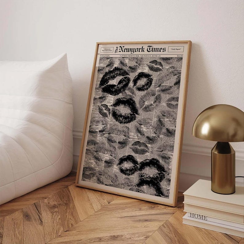 Puede incluir: Un estampado enmarcado con un collage de marcas de besos de l&aacute;piz labial negro sobre un fondo de peri&oacute;dico vintage. El estampado est&aacute; en un marco de madera clara. El peri&oacute;dico dice "New York Times".