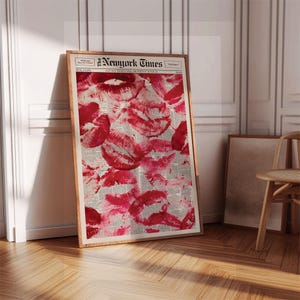 Pu&ograve; includere: Una stampa incorniciata con un collage di impronte di baci di rossetto rosso su uno sfondo di giornale. La stampa &egrave; in una cornice di legno e include il testo "New York Times". L'estetica generale &egrave; moderna e artistica.