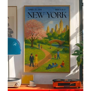 May include: A framed art print of a park scene in New York City. The artwork features a path, bridge, and cityscape under a blue sky. The text "APRIL 25, 1994 NEW YORK PRICE $1.5" is at the top.