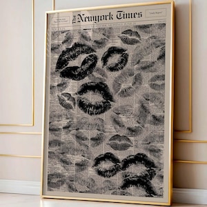 Puede incluir: Impresi&oacute;n enmarcada con marcas de besos de l&aacute;piz labial negro sobre un fondo de peri&oacute;dico vintage. El peri&oacute;dico se titula "The New York Times" y est&aacute; fechado el "21 de junio". La impresi&oacute;n est&aacute; en un marco dorado.
