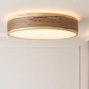 Könnte beinhalten: Eine kreisförmige Deckenleuchte mit einem breiten Holzrahmen, der eine natürliche Maserung und dunkle Streifen aufweist. Die Mitte der Leuchte besteht aus einem flachen, runden weißen Diffusor, der ein sanftes, warmes Licht abgibt.