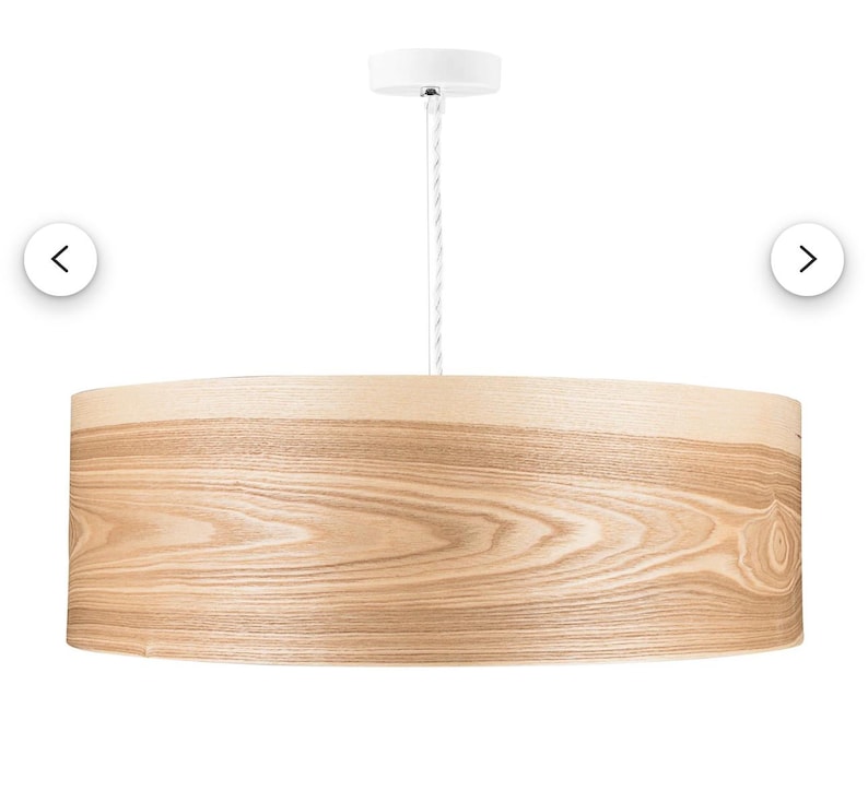 May include: A cylindrical pendant light fixture featuring a light-toned wood veneer shade with a visible natural grain pattern. The drum-shaped shade is suspended by a white cord connected to a matching white circular ceiling canopy mount.