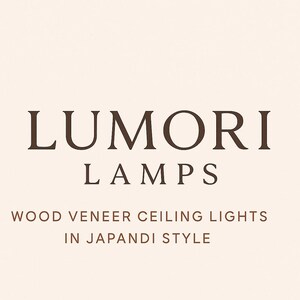 May include: A graphic design featuring the dark brown text LUMORI LAMPS followed by the text WOOD VENEER CEILING LIGHTS IN JAPANDI STYLE on a light cream background. The typography is clean and centered, presenting the brand name and product category.