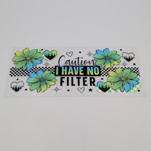 May include: A rectangular sticker with the text "Caution I HAVE NO FILTER" in black and white. The sticker features colorful flowers, hearts, stars, and a checkered pattern.