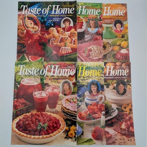 May include: A white ceramic mug with a black handle and the text "But First, Coffee" in a bold, black font. The mug is set against a blurred background, suggesting a cozy setting.