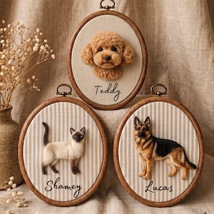 Può includere: Tre telai ovali in legno con ritratti di animali realizzati con infeltrimento ad ago su tessuto. Un telaio mostra un barboncino marrone etichettato Teddy, un altro un gatto siamese etichettato Shamey e il terzo un pastore tedesco etichettato Lucas.