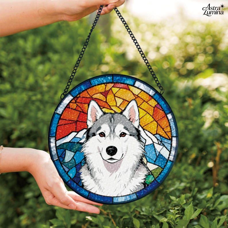 May include: Circular stained glass window art depicting a Siberian Husky dog. The artwork has a colourful mosaic design with a mountain and sunset backdrop. The piece is held by a black chain and is suitable for hanging.