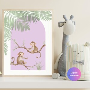 May include: A framed print showing two cartoon monkeys on a branch, set against a lilac background with green palm leaves. The print is labelled "Digital Download" and is next to a stuffed giraffe and bear.