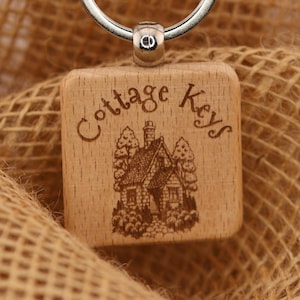 May include: Wooden keychain with a silver ring, featuring a square wooden charm engraved with "Cottage Keys" and a cottage illustration. The tag above reads "T&A Creative Concepts LLC" and "tacreativeconceptsllc.com".