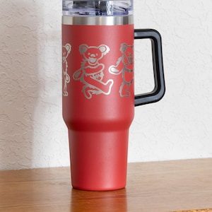 May include: Red insulated tumbler with a black handle and lid. The tumbler features a silver design of dancing bears. Includes a black straw. The tumbler is designed to keep beverages cold or hot.