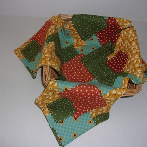 May include: A patchwork fabric square with a variety of patterns and colors, including green, orange, yellow, and blue. The fabric is draped over a woven basket, creating a rustic and cozy aesthetic.