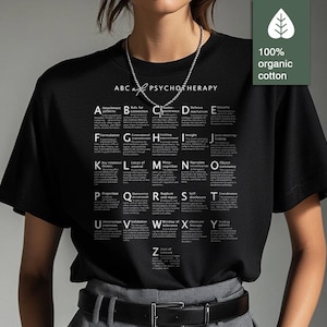Könnte beinhalten: Schwarzes T-Shirt mit dem weißen Text "ABC of Psychotherapy", das psychologische Begriffe von A bis Z auflistet. Das Shirt besteht aus 100% Bio-Baumwolle.