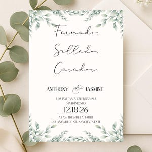 May include: A white wedding invitation card featuring green watercolor leaf illustrations at the top and bottom. The text reads: Firmado, Sellado, Casados, ANTHONY & JASMINE, LES INVITAN A CELEBRAR SU MATRIMONIO, 12.18.26, A LAS TRES DE LA TARDE, 123 ANYWHERE ST. ANYCITY, STATE.
