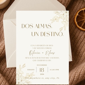 K&ouml;nnte beinhalten: Elfenbeinfarbene Hochzeitseinladung mit goldenen floralen Akzenten und Text. Die Einladung lautet "Dos Almas, Un Destino" und enth&auml;lt die Namen Olivia und Elias sowie das Datum 18. Dezember 2026 und die Uhrzeit 17:00 Uhr.