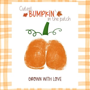 Puede incluir: Una impresión rectangular con un borde de cuadros en naranja claro y blanco. El centro muestra dos huellas de manos naranjas que forman una calabaza con un tallo verde y zarcillos. El texto dice: Cutest BUMPKIN in the patch y GROWN WITH LOVE.