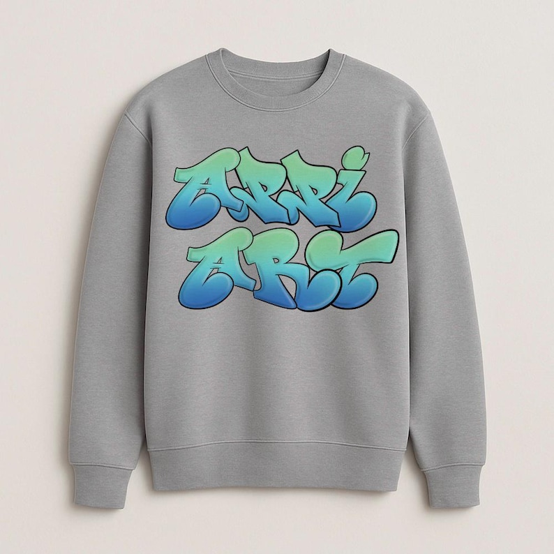 May include: A gray sweatshirt with the word "ARRI ART" in a graffiti-style font. The text is gradient, transitioning from blue to green. The sweatshirt has a crew neck and long sleeves.