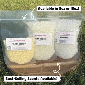 May include: Three clear plastic bags filled with aroma beads, each labeled with a different scent: Black Cherry, Butt Naked, and Leather. The bags are on a wooden surface, with text indicating they are available in 8oz or 16oz sizes.