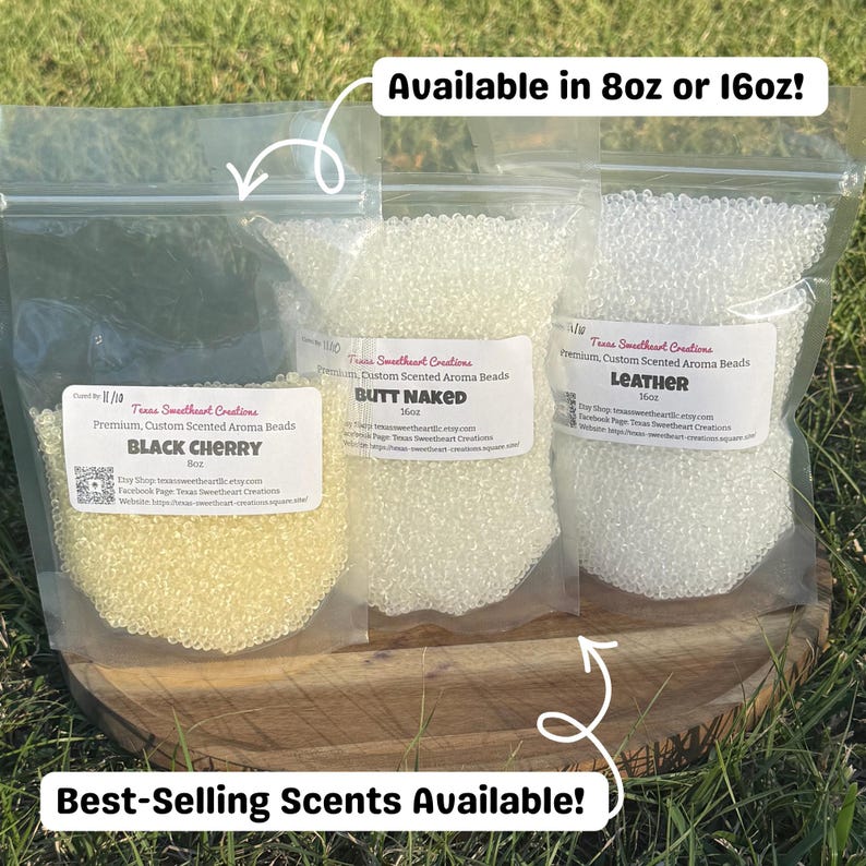 May include: Three clear plastic bags filled with aroma beads, each labeled with a different scent: Black Cherry, Butt Naked, and Leather. The bags are on a wooden surface, with text indicating they are available in 8oz or 16oz sizes.