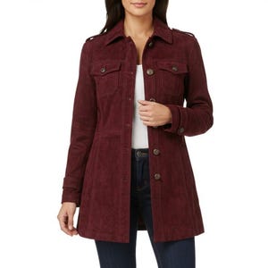 May include: A burgundy suede jacket with a collared neckline, button-down front, and two chest pockets. The jacket has long sleeves with buttoned cuffs and a tailored fit. The model is wearing dark blue jeans.