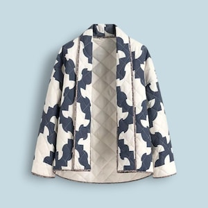 Op de afbeelding: Gewatteerde jas met een crèmekleurig en marineblauw geometrisch patroon. De jas met open voorkant heeft een geometrisch ontwerp en een gewatteerde voering. Een stijlvol bovenkledingstuk.