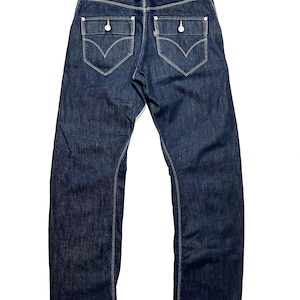 Puede incluir: Vaqueros de mezclilla azul oscuro con un diseño clásico de cinco bolsillos. Incluyen bolsillos traseros con solapa abotonada, una etiqueta roja de Levi's y bragueta con botones. Corte recto.