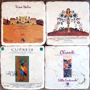 May include: Four square, white marble coasters with colorful images and text. The coasters feature images of a house, a tree, a bird, and a vineyard. The text on the coasters includes "Vino Italia", "Contessa Entellina", "Cuprese", and "Chianti".
