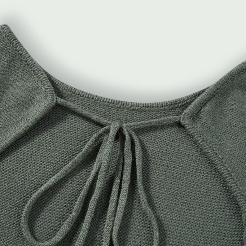 Peut inclure: Gros plan sur un haut en tricot vert sauge avec un col carr&eacute; et un d&eacute;tail de n&oelig;ud. Le tissu est doux et textur&eacute;. Le col et le n&oelig;ud sont les points centraux du design.