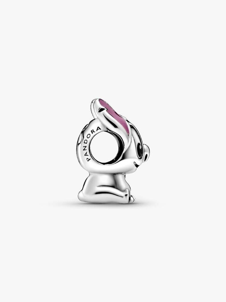 May include: A silver charm in the shape of a rabbit, with a pink accent on its ear. The charm has a hole for threading onto a bracelet or necklace. The word "Pandora" is engraved on the side.