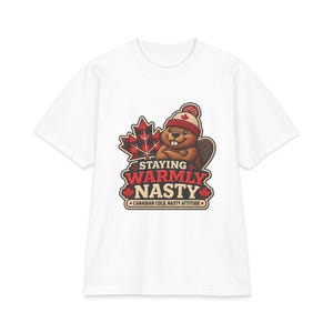 May include: A white t-shirt featuring a graphic of a brown beaver wearing a red and white knit hat with a maple leaf. Behind the beaver is a red and black plaid maple leaf. The text reads STAYING WARMLY NASTY and CANADIAN COLD, NASTY ATTITUDE.
