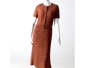 May include: A brown knitted dress with short sleeves and a belt. The dress has a textured, woven fabric.