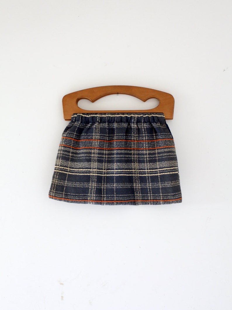 May include: A plaid fabric bag with a wooden handle. The bag is blue, white, and orange.