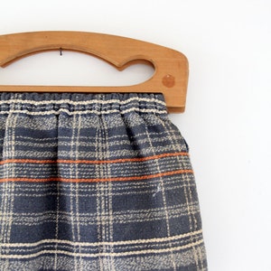 May include: A vintage wooden framed handbag with a plaid fabric lining in shades of blue, white, and orange.